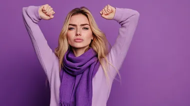 Profile view of an angry blonde woman with a purple scarf around her neck protesting raising her arms on purple background with plenty of copy space, international women's day