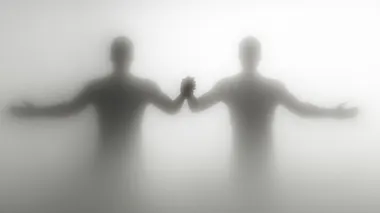 two figures holding hands behind a frosted glass, on a white background