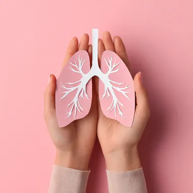 Female hands holding paper lungs on pink background. Lung cancer concept