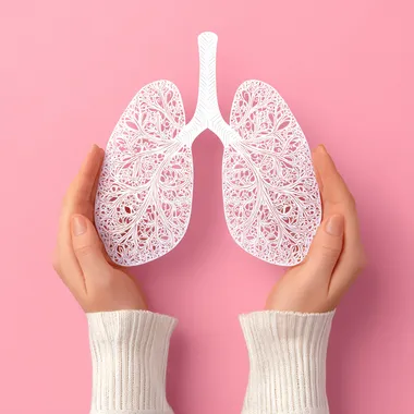 Female hands holding paper lungs on pink background. Lung cancer concept