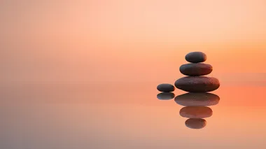 four stacked flat zen stones on a reflective surface at sunrise, soft orange-pink sky, reflective surface and sky should dominate, silent image, stones flat and small, peaceful minimalist composition, gentle gradient lighting, calm atmosphere, smooth textures  a2dpl3p   --s 22