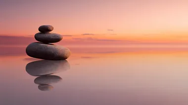 four stacked flat zen stones on a reflective surface at sunrise, soft orange-pink sky, reflective surface and sky should dominate, silent image, stones flat and small, peaceful minimalist composition, gentle gradient lighting, calm atmosphere, smooth textures  a2dpl3p   --s 22