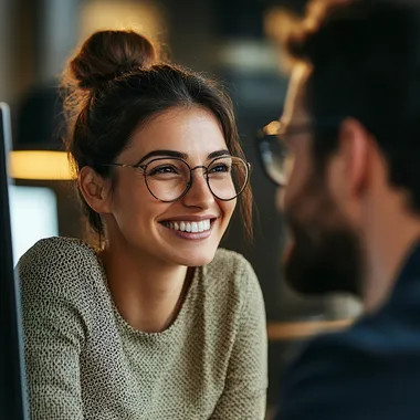woman looking away from computer screen looking at colleague smiling