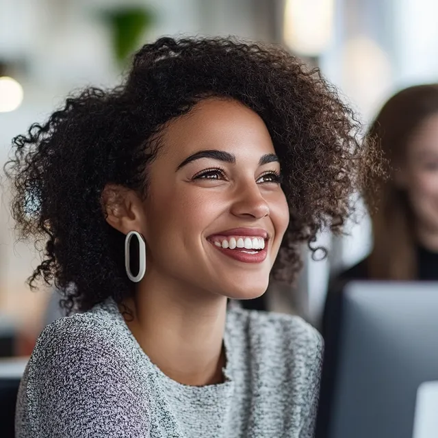 Smiling woman in home office glances at colleague while working