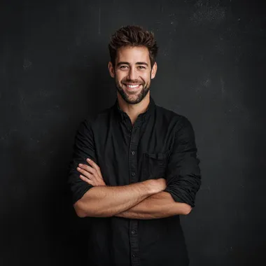 happy young man looking at front wearing shirt with hands crossed and solid black as the background