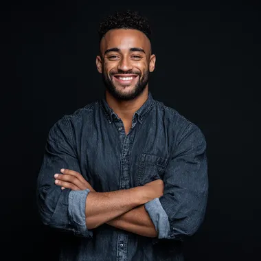 happy young man looking at front wearing shirt with hands crossed and solid black as the background