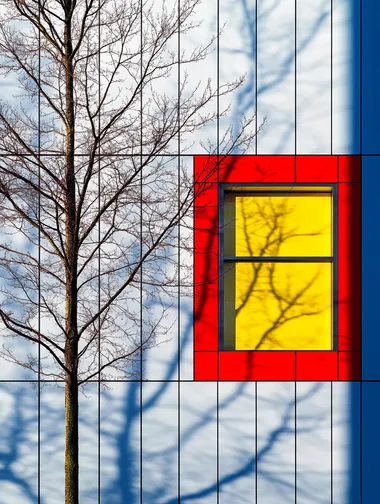 Minimalist, colorful photograph of a house wall with a tree, featuring a white and red color scheme, a blue sky, bold geometric shapes, high contrast, and a bright yellow window. This architectural photography was captured using a Hasselblad X2D camera.