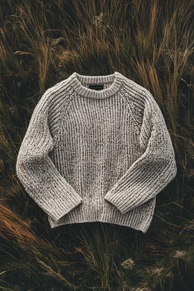 A knitted jumper packshot from above on top of a scottish highland grass, studio lighting, shot from above