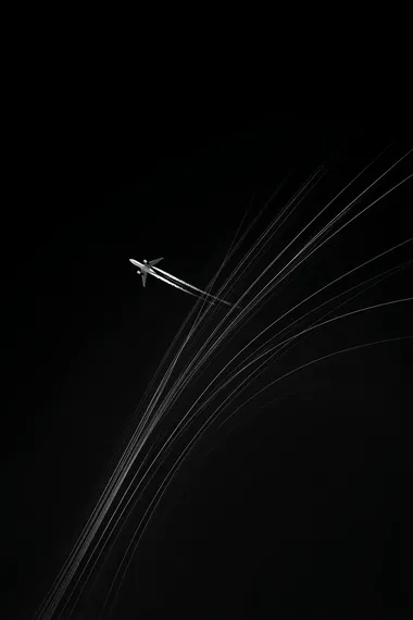 An airplane flying in the sky, leaving trails behind it, against a black background, in the style of white on dark grey.