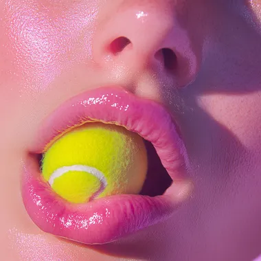 A woman's tongue is sticking out and holding a rose petal in her mouth, a pink aesthetic photo with a close-up of an open girl's lips against a white background, in the style of an Instagram story. A close-up of a tennis ball on the side of a beautiful female face, a pink pastel aesthetic photo