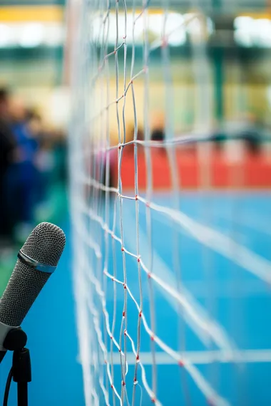 a close up of a microphone in the foreground, with a an attentive crowd in the background. Hip office setting, background is blurred