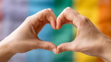 Hands making heart sign in front of rainbow flag, high-resolution, ultra-high quality Depth & Sharpness, no logos, bright lighting, soft shadows, perfect for stock photo.  --raw rofile d3xh2hv