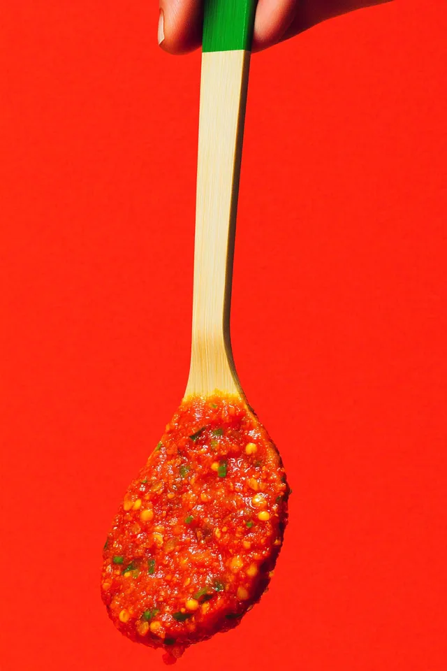 Hand Holding Wooden Spoon with Korean Gochujang in Kitchen Setting