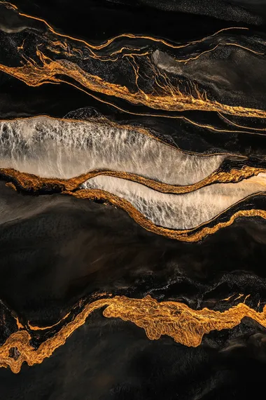 Evening scene, black sand beach with white and golden waves, high-angle aerial perspective, dramatic contrast, serene yet striking ocean scenery, soft twilight lighting, warm golden hues blending with dark tones, cinematic composition, ultra-realistic details, vibrant colors, dynamic textures, ethereal and majestic atmosphere, glowing waves under the fading light.  --s 50