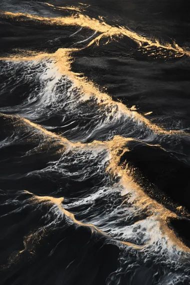 Evening scene, black sand beach with white and golden waves, high-angle aerial perspective, dramatic contrast, serene yet striking ocean scenery, soft twilight lighting, warm golden hues blending with dark tones, cinematic composition, ultra-realistic details, vibrant colors, dynamic textures, ethereal and majestic atmosphere, glowing waves under the fading light.  --s 50