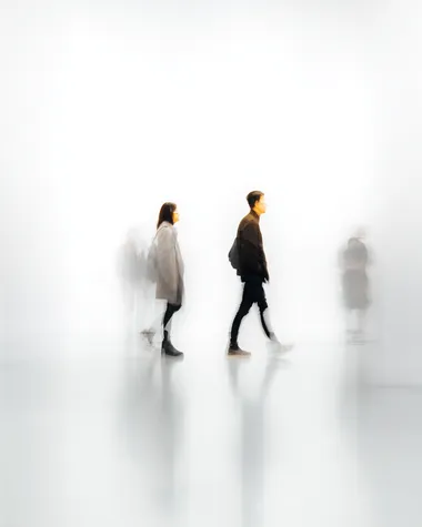 Blurred human figures in motion, against a white background with minimalist text, creating an abstract and artistic composition. The blurred images of the people create depth and movement within the scene while also serving as visual elements for design or graphic work. The overall effect is one that captures both contemporary aesthetics and emotional essence through its simplicity and minimalistic approach.