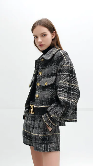 A young female model is wearing a Chanel brand woolen short jacket, with a dark gray and black checkered pattern and gold buttons, in a loose shape, with a light, luxurious style and a minimalist aesthetic, against a white background. The outfit is in the style of Dior.   --raw