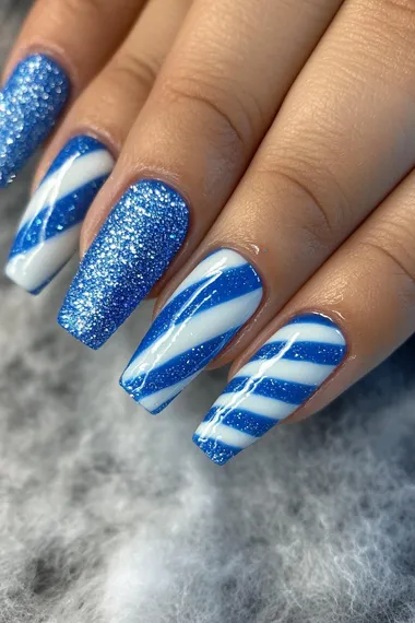 A photo of a woman's hand with long coffin nails with sparkly textured glitter of blue and white candy cane stripes