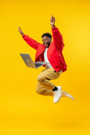 A person leap and holding a laptop, smiling, full-body shot, yellow background, studio photography, advertising style, high-resolution photography.