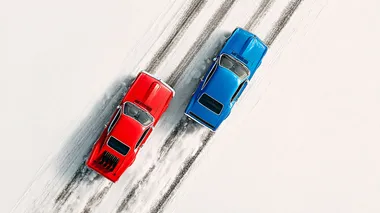 Sleek red 1969 Ford Mustang racing a blue 1991 Pntiac Firebird side by side leaving tire trails against a white backdrop behind the cars, top-down view creating a racing scene, cars are moving from left to right. retro feeling similar to 1970's car promotional posters, minimalist