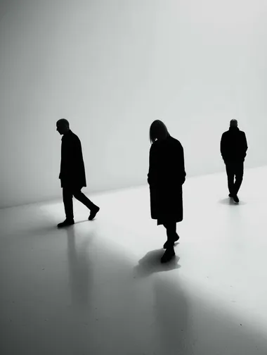 Three people walking on a white floor, shadows, wearing black clothes and contrasting with the background, no shadow, white clean background, Looking at different places, one person is in agony  rofile eo8b66r