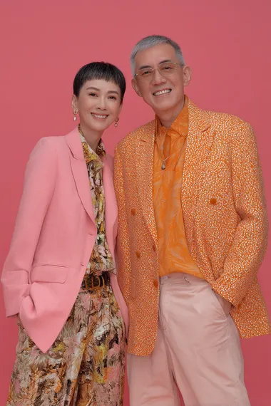 a front shot of a lovely, modern, cheerful. good looking 70 years old asian model couples in a young modern look, pink and orange blazer  o9smv9f