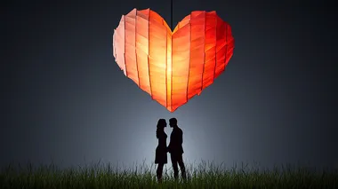 Silhouetted lovers standing under a glowing heart chandelier on a dark gray background , space for text  2231e8s     --s 250