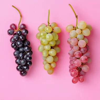 detailed photo of red wine grape, white wine grape and pink wine grape over a pink background