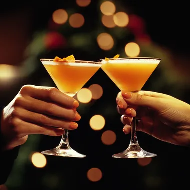 two hands holding two frothy orange martini's must look like a club like photo, high energy and realistic