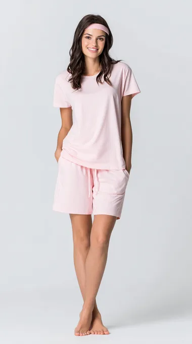 Front shot of slim woman model wearing premium soft cotton pajamas, short sleeved top, extremely comfortable fit, knee length shorts, simple white background, clean studio lighting, fashion product showcase style
