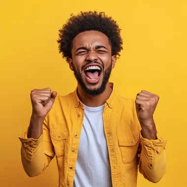 Cheerful ethiopian man with afro dressed casual clothes celebrate success raise hands fists isolated on golden color background. he is between 20 to 30 years old. he is good looking . he is screaming with his mouth slightly open . he have dark skin . he have ethiopian skin tone