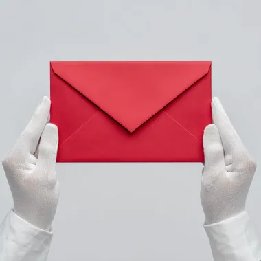 Two hands wearing white silk gloves holding an big red envelope, white background, top View