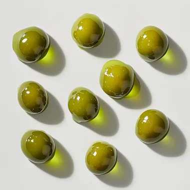 Hyper realistic green olives ont olive oil drops on them on white baclground