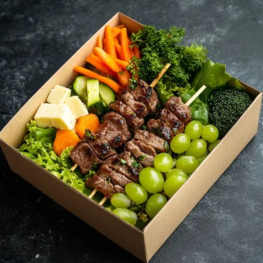 The food box has lettuce base, 3 beef skewers and vegetables on top, along with some boiled broccoli, boiled carrots, and 1 small bunch of green grapes. Place inside a paper box. The most realistic image