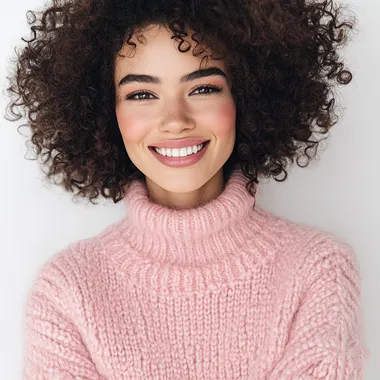 Realistic photograph of a beautiful 30-year-old European woman with curly hair wearing a pastel pink pop jumper and smiling. The woman is posed. The background must be white and the photograph must be taken in 4 --s 50