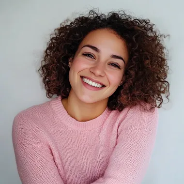 Realistic photograph of a beautiful 30-year-old European woman with curly hair wearing a pastel pink pop jumper and smiling. The woman is posed. The background must be white and the photograph must be taken in 4 --s 50