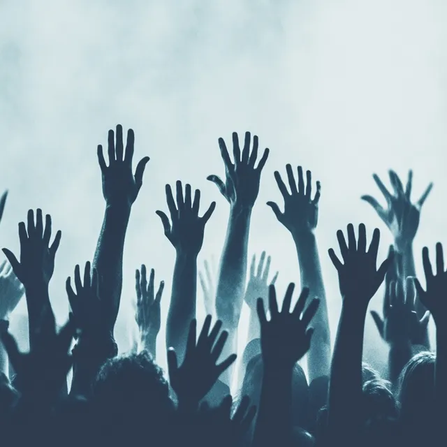 Festival crowd with hands raised in the air, vibrant LED stage visuals