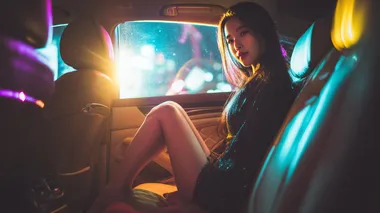 Beautiful Chinese girl with modern fashion sitting in a brightly lit car, modern car interior. Girl wearing short skirt. Dark outside