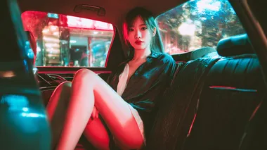 Beautiful Chinese girl with modern fashion sitting in a brightly lit car, modern car interior. Girl wearing short skirt. Dark outside
