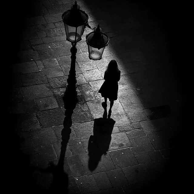 Shadow of a Woman Walking Alone Under Street Lamp in Urban Setting