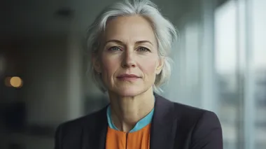 A professional portrait of a confident middle-aged businesswoman, elegantly dressed in a tailored blazer and silk blouse, featuring a custom color palette of warm coral-orange (#F98A71), deep purple (#9265C4), soft cream (#F2ECCE), and vibrant turquoise-green (#6BF2C1). Her poised and determined expression conveys leadership and wisdom. Her short, well-styled hair frames her face, and subtle makeup enhances her natural features. The softly blurred background showcases a modern office with large windows, reflecting hues of the custom color scheme. Cinematic and high-end corporate feel, shot with a Canon EOS R5, 85mm f/1.2 lens, shallow depth of field, natural and balanced lighting, photorealistic textures   rofile d7sot8n