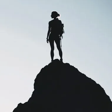 Silhouette of a fit woman standing on top of a peak, minimalist, hiking gear, light and shadows